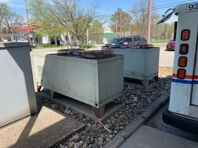 Two older outdoor commercial HVAC units on a gravel pad by Allstate Heating & Cooling in Lexington, KY.