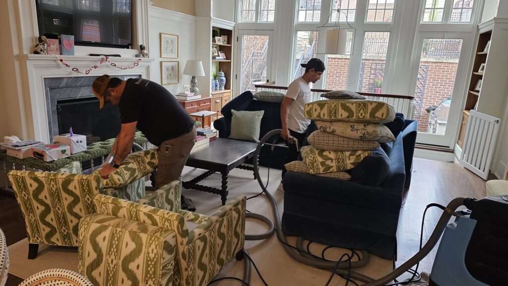 Two technicians performing on-site upholstery cleaning for chairs and a sofa at a client's home by Personal Touch Carpet Cleaning in Chicago, IL.