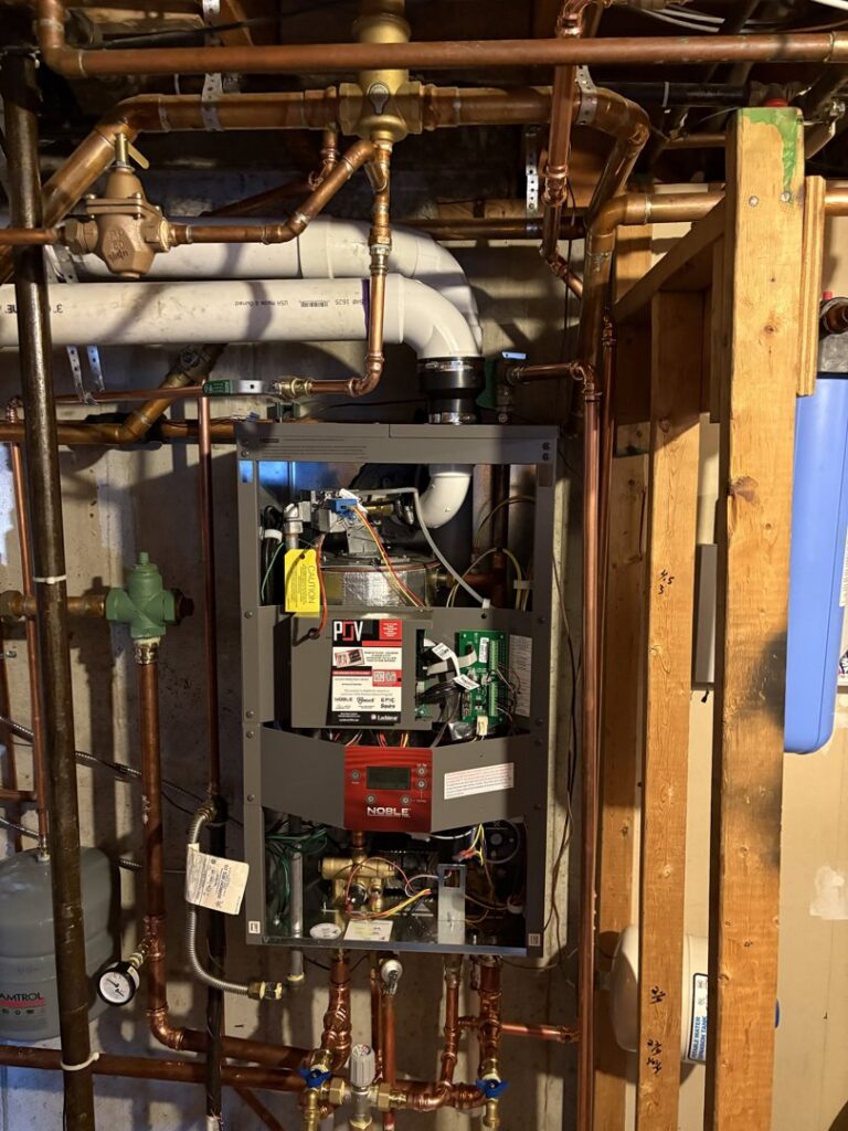An open boiler unit showing internal components and copper piping during service or installation by All In One Home Services in Denver, CO.