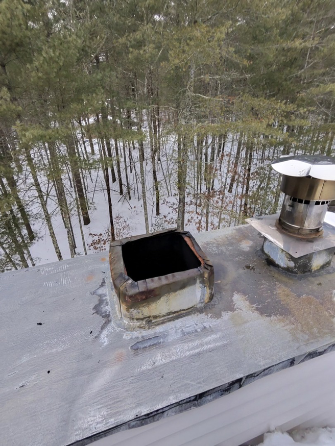 An open chimney flue on a snowy roof, ready for inspection or sweeping by Certified Masons in Warwick, RI