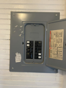 An open electrical breaker panel on a wall, showing components an electrician from Charging Rhino Electric in Mobile, AL would service
