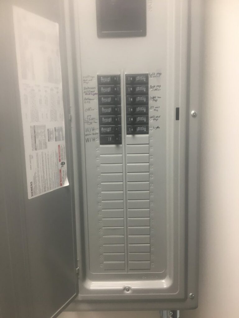 An open electrical breaker panel with handwritten circuit labels, serviced by Goodie's Electrical Contractors LLC in Dothan, AL