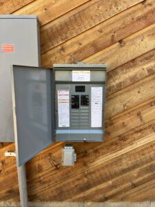 An open electrical breaker panel showing circuit breakers and wiring on a wooden wall, installed by Mountain Electric in Knoxville, TN.