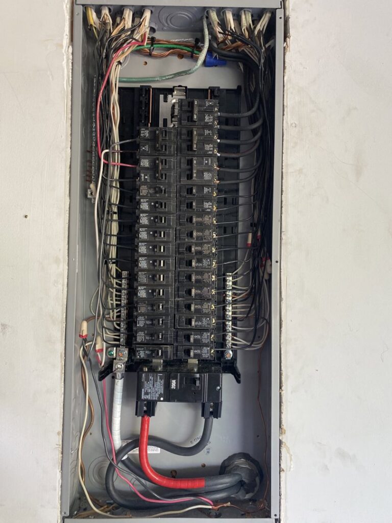 An open electrical breaker panel showing extensive wiring and circuit breakers, serviced by Shocking Solutions in Knoxville, TN.