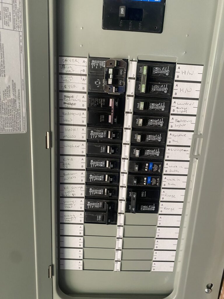 An open electrical breaker panel showing circuit breakers and labels, installed by Kot Electric LLC in Kent, WA.