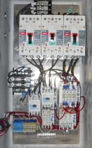 An open electrical control panel showing intricate wiring, circuit breakers, and relays, expertly installed by Basic Supply in Lafayette, LA.