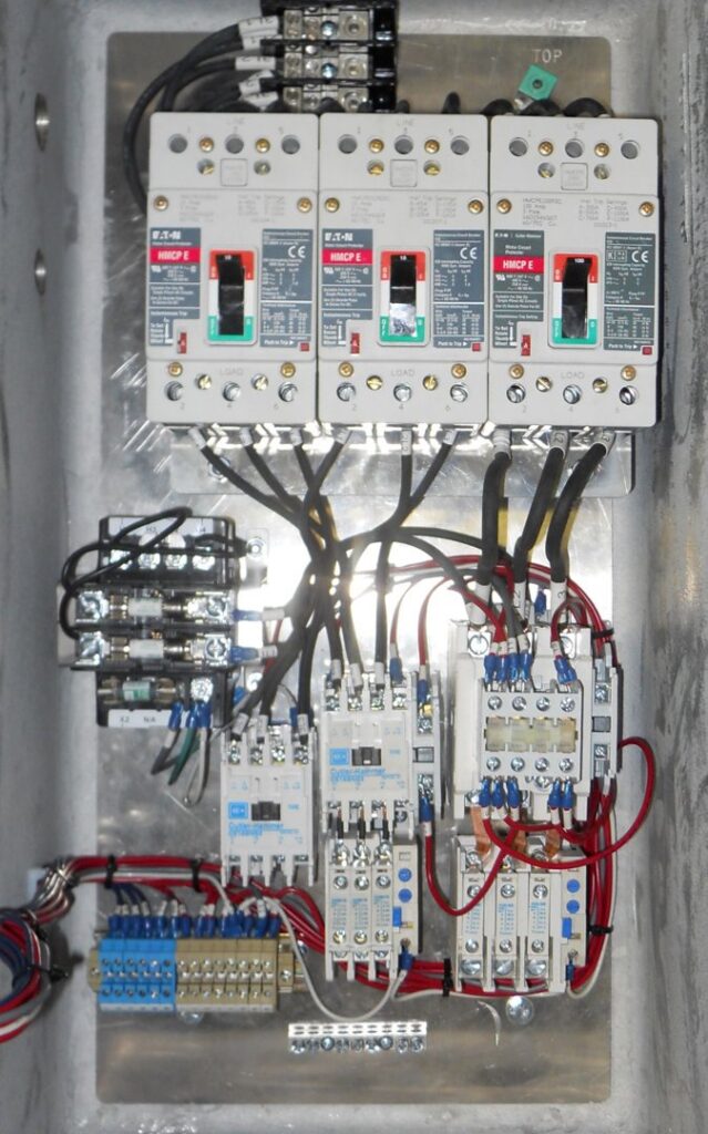 An open electrical control panel showing intricate wiring, circuit breakers, and relays, expertly installed by Basic Supply in Lafayette, LA.