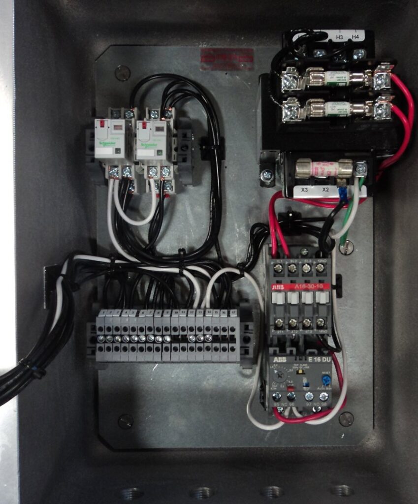 An open electrical control panel displaying organized wiring, relays, and terminal blocks, a typical job by Basic Supply in Lafayette, LA.