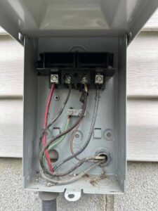 An open electrical disconnect box next to an outdoor AC unit being serviced by Allegiance Heating & Air in Greenville, IN.