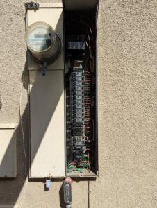 An open electrical panel and meter on an exterior wall, showcasing electrical service by Primo's Electrical Services in San Diego, CA.