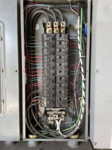 An open electrical panel showing circuit breakers and wiring, indicating electrical service by Ernco Electric Inc. in Fresno, CA.