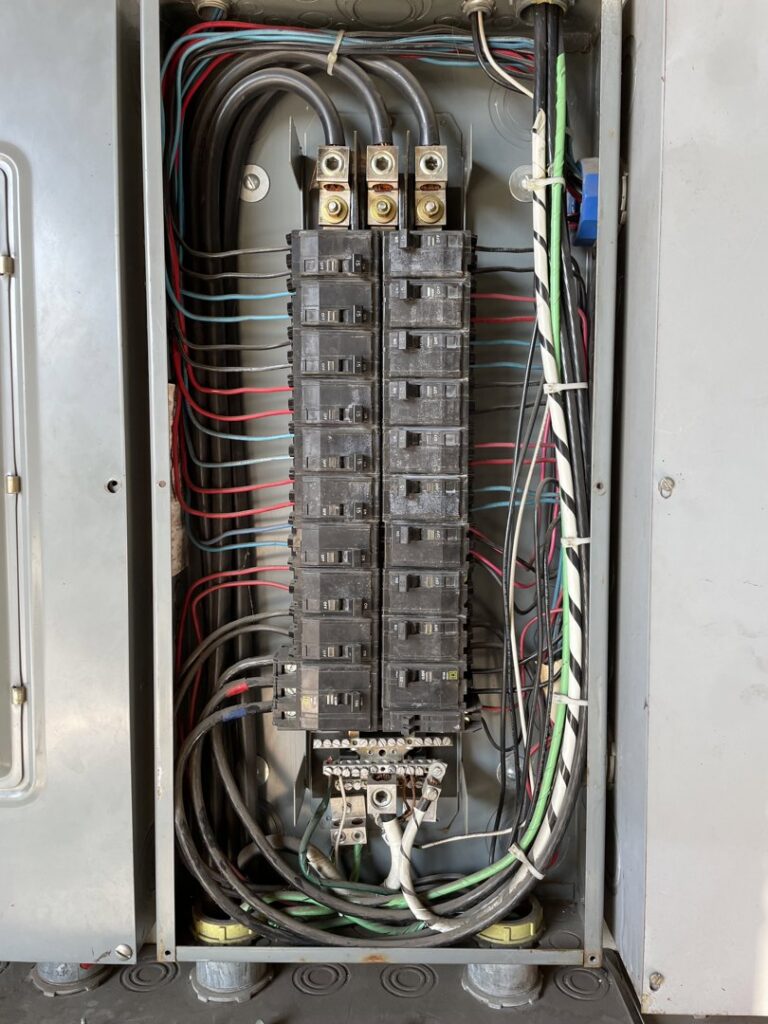 An open electrical panel showing circuit breakers and wiring, indicating electrical service by Ernco Electric Inc. in Fresno, CA.
