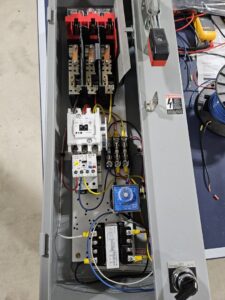 An open electrical panel showing intricate wiring, contactors, and relays, serviced by Apex Electric LLC in Brea, CA.