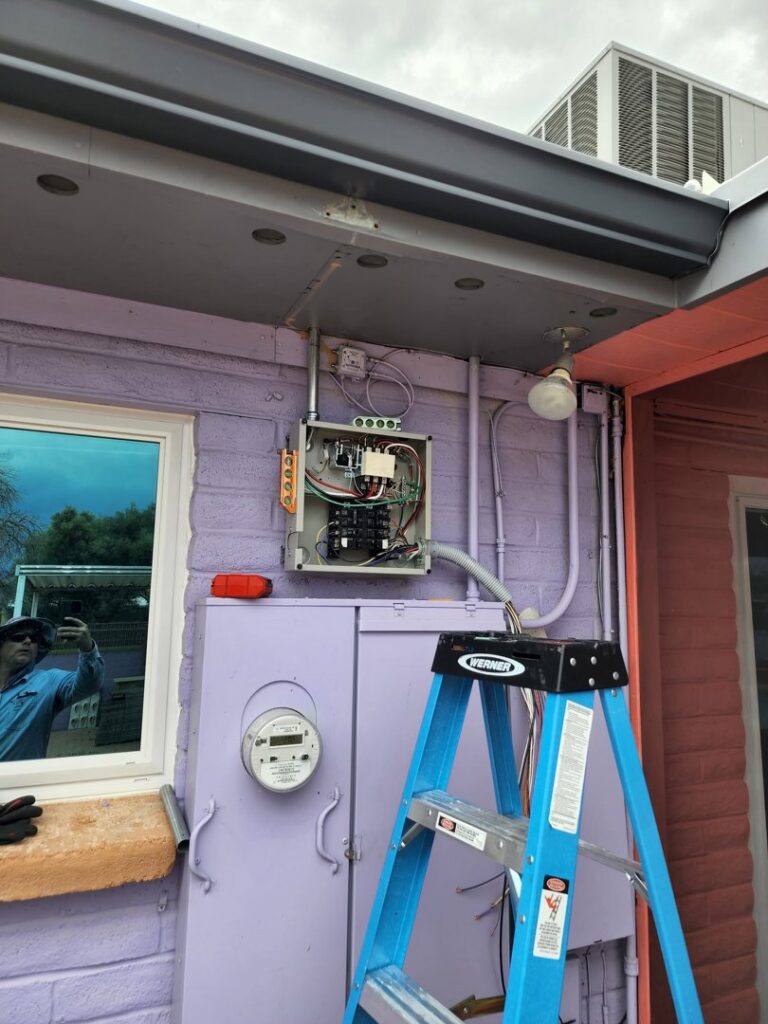 An open electrical panel showing wiring and a meter, with a ladder nearby, indicating work by CDB Electrical LLC in Tucson, AZ.