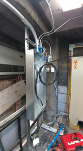 An open electrical panel with wiring and conduit, showing tools on the floor by Triumph Electrical Services, Inc in Minneapolis, MN