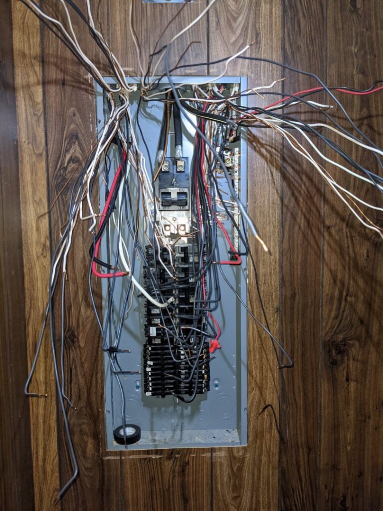 An open electrical panel with complex wiring and circuit breakers, showcasing electrical expertise by GOBE LLC in Columbia, MO.