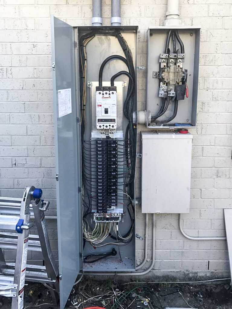 An open electrical panel with visible wiring on the exterior of a building, serviced by Steadfast Electric, LLC in Baton Rouge, LA.