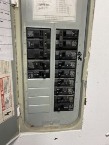 An open electrical panel displaying circuit breakers and a danger warning, indicating service by AA Electric Contractors in Chicago, IL.