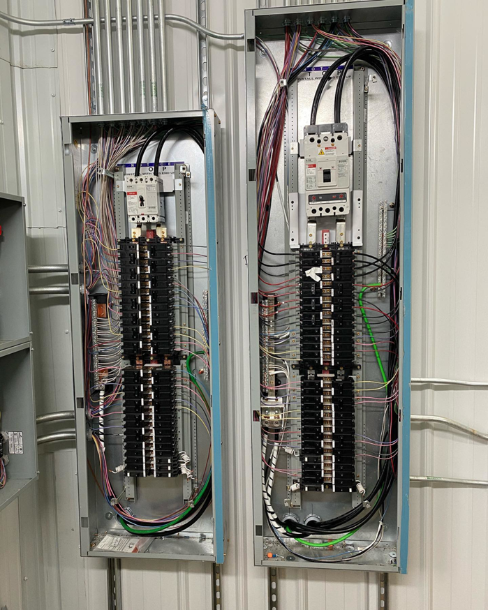 Open electrical panels with intricate wiring and conduits installed by Tallent Electrical Services in Tulsa, OK