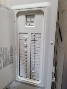 An open electrical service panel displaying numerous circuit breakers, indicating professional electrical work by 8Thirty Electric, Inc. in Johns Creek, GA.