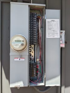 An open electrical service panel and meter on an exterior wall, indicating professional electrical work by Primo's Electrical Services in San Diego, CA.
