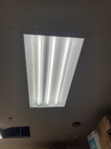 An open fluorescent light fixture with visible tubes in a commercial ceiling by Balderas Electric in Austin, TX.