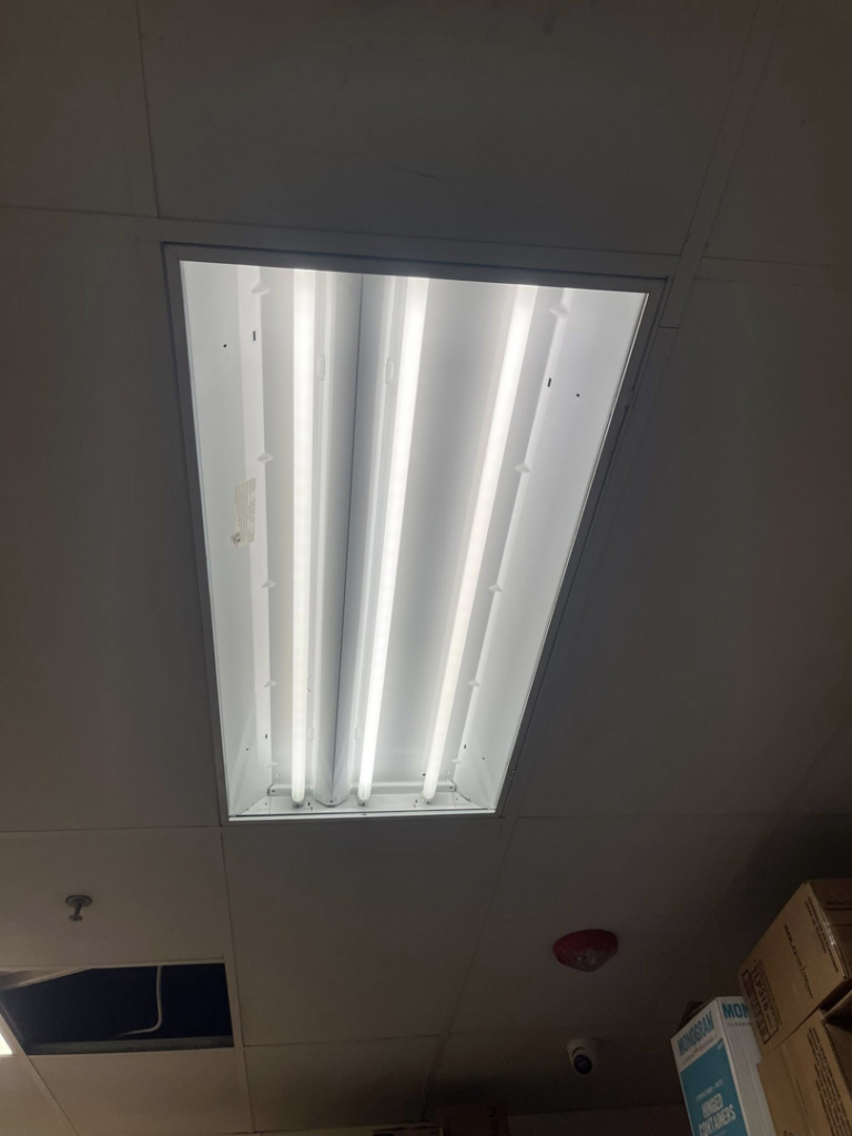 An open fluorescent light fixture with visible tubes in a commercial ceiling by Balderas Electric in Austin, TX.