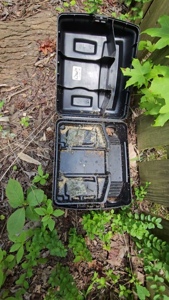 An open pest control bait station placed outdoors for rodent or insect management by 1 Pest Solution in Winston-Salem, NC.