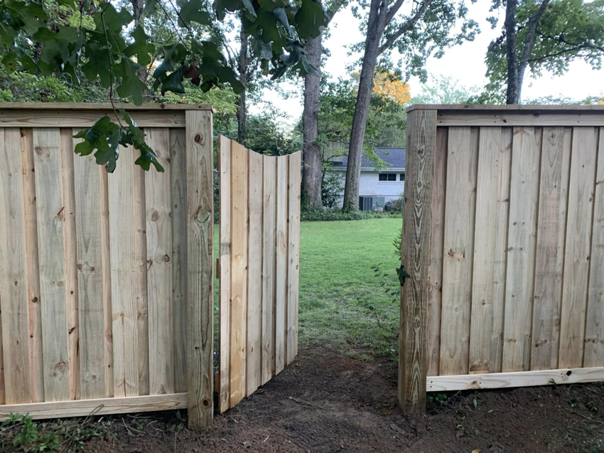 An open natural wood privacy fence gate installed by Brock Brothers Fence, leading to a backyard in Mobile, AL.