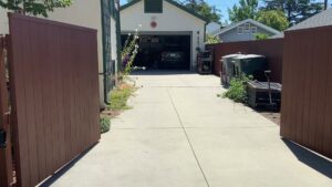 An open wooden driveway gate providing access to a garage, installed by Harwell Fencing & Gates Inc. in Los Angeles, CA.