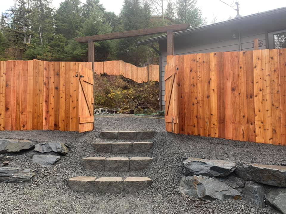 Open wooden privacy fence gates leading to a landscaped area, installed by Baranof Landscaping in Sitka, AK.