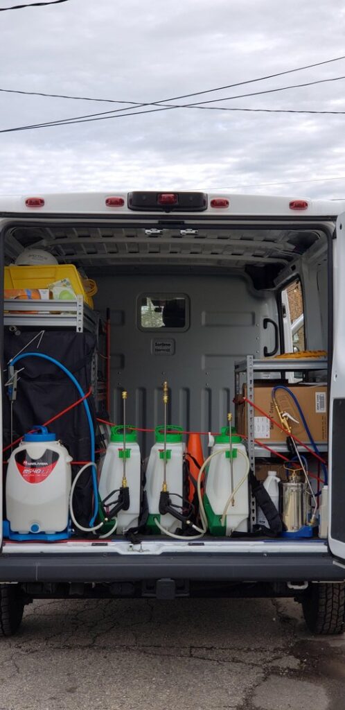 Organized pest control equipment, including multiple sprayers, visible in the back of a service van for Spectrum Pest Control Eco-Tech LLC in Kenosha, WI.