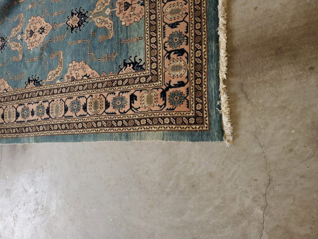 A detailed view of the edge of an ornate oriental area rug on a concrete floor by Right & Clean Atlanta 24-7 Carpet Cleaning in Atlanta, GA.