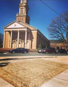 A large oriental rug laid out on the sidewalk, possibly for cleaning or display, by Robert Fritz Oriental Rugs, Inc. in Raleigh, NC