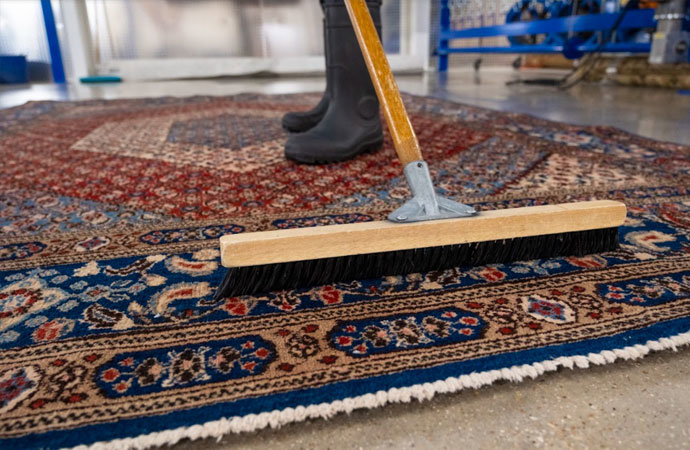 An oriental rug being cleaned with a large brush by GTS future cleaning services in Los Angeles, CA