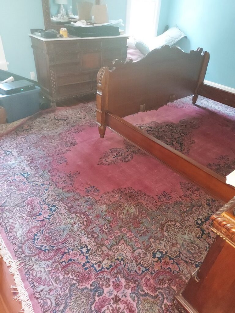 A beautifully installed oriental rug with intricate patterns in a bedroom by Pars Rugs Savannah, GA.