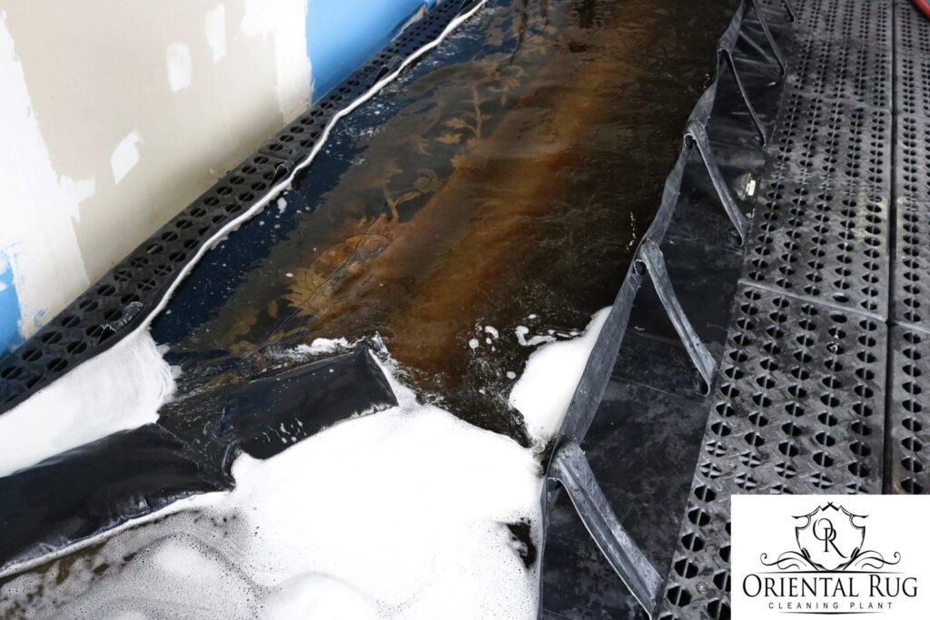 An oriental rug soaking in a cleaning solution during the deep wash process at Oriental Rug Cleaning Facility in Tampa, FL