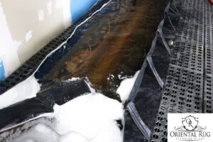 An oriental rug soaking in a cleaning solution during the deep wash process at Oriental Rug Cleaning Facility in Tampa, FL