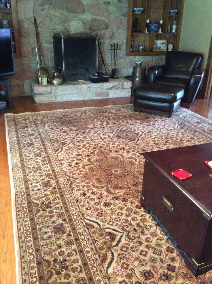 A large oriental rug complementing a living room with a stone fireplace and leather furniture, installed by Brandon Oriental Rugs, Furlong, PA.