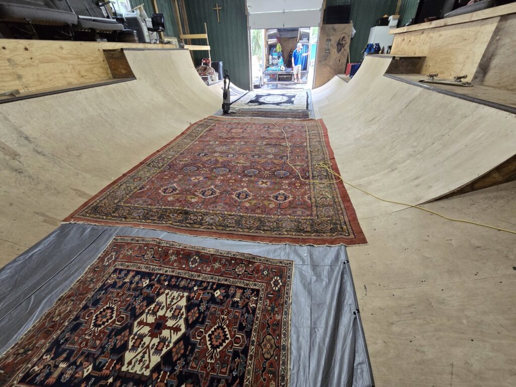 Several oriental rugs laid out on a tarp, prepared for professional cleaning service by Inspection Ready LLC in Bellevue, NE.