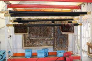 Multiple oriental rugs hanging on drying racks with air movers at Oriental Rug Cleaning Facility in Tampa, FL