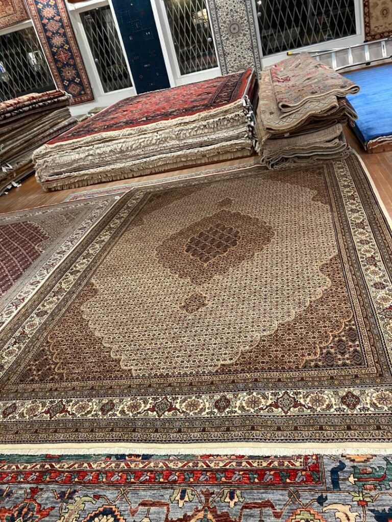 Various oriental rugs stacked and displayed in the gallery of J and J Oriental Rug Gallery in Alexandria, VA.