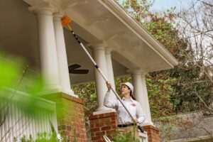 An Orkin Pest Control technician treating the eaves of a house for pests and cobwebs in Jonesboro, AR.
