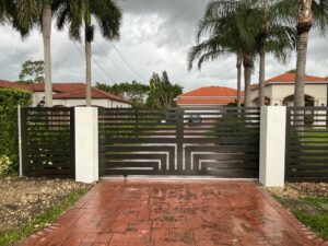 An ornamental black driveway gate with a geometric design installed by Osuna Ornamental Fences & Gates in Cutler Bay, FL.
