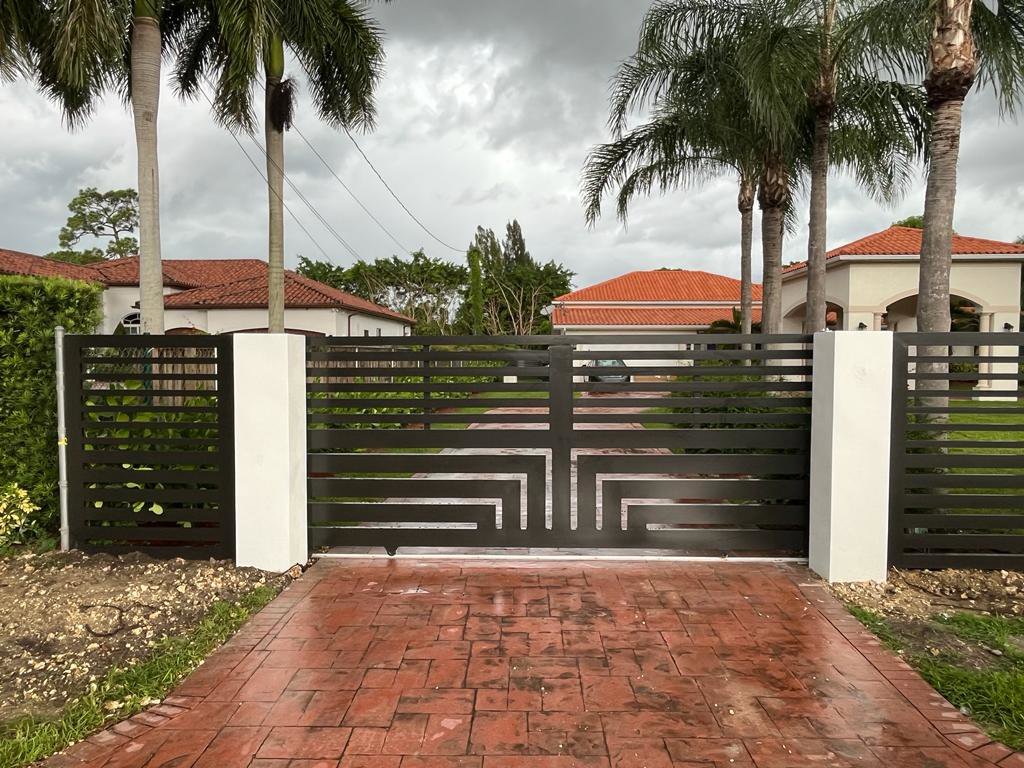 An ornamental black driveway gate with a geometric design installed by Osuna Ornamental Fences & Gates in Cutler Bay, FL.