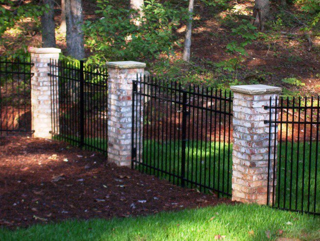 An elegant ornamental iron fence with decorative brick pillars installed by D-Fence of Tulsa in Tulsa, OK.