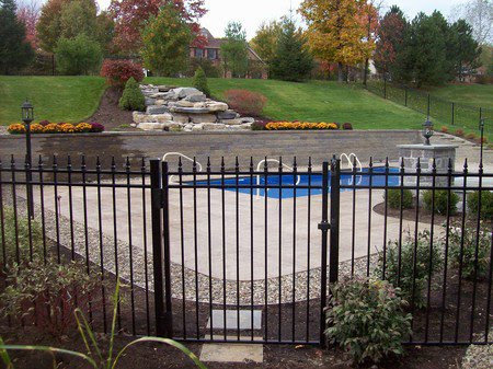 A black ornamental iron fence with a gate securing a swimming pool area by D-Fence of Tulsa in Tulsa, OK.