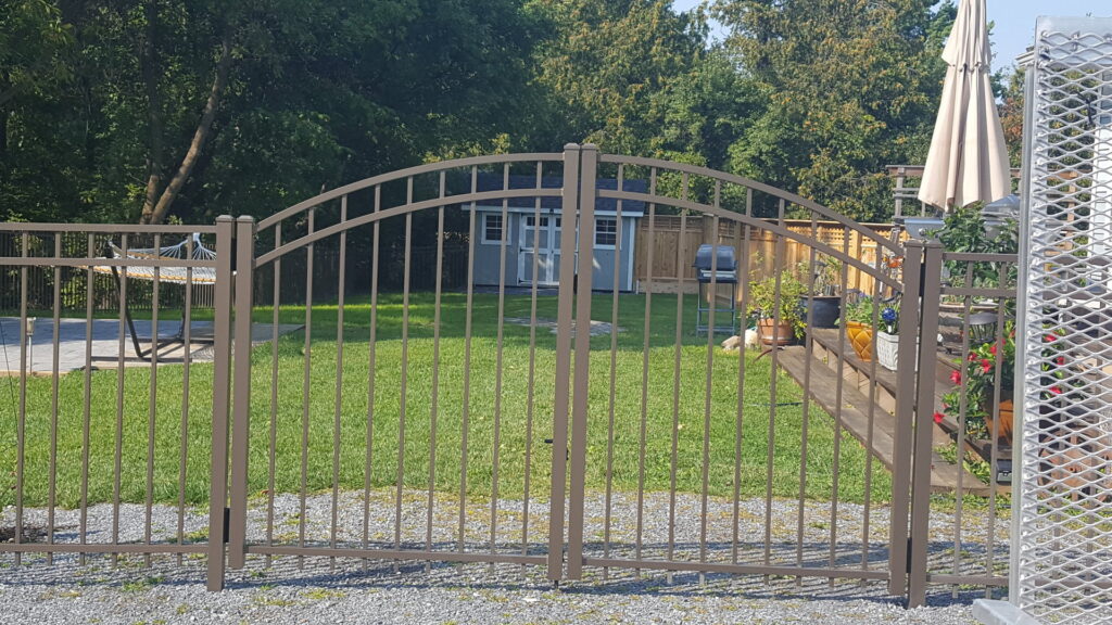 An ornamental metal double gate and fence section installed in a backyard by 802 Fence Company LLC in Shoreham, VT.