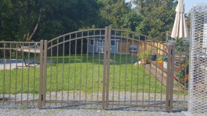 An ornamental metal double gate and fence section installed in a backyard by 802 Fence Company LLC in Shoreham, VT.