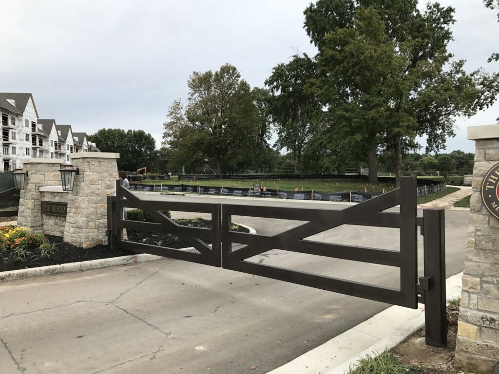 A large ornamental metal entrance gate with stone pillars installed by Roy & Son Fencing in Lee's Summit, MO.
